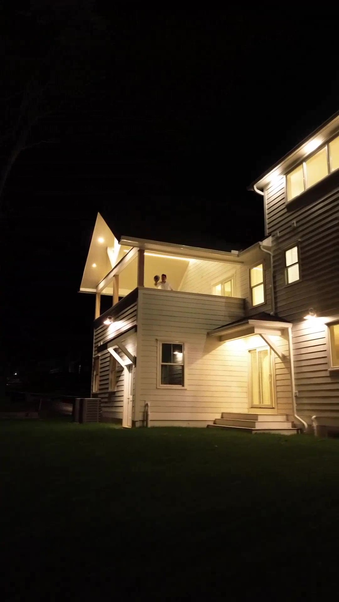 People gathered, lit, on the porch of a More Life home at night